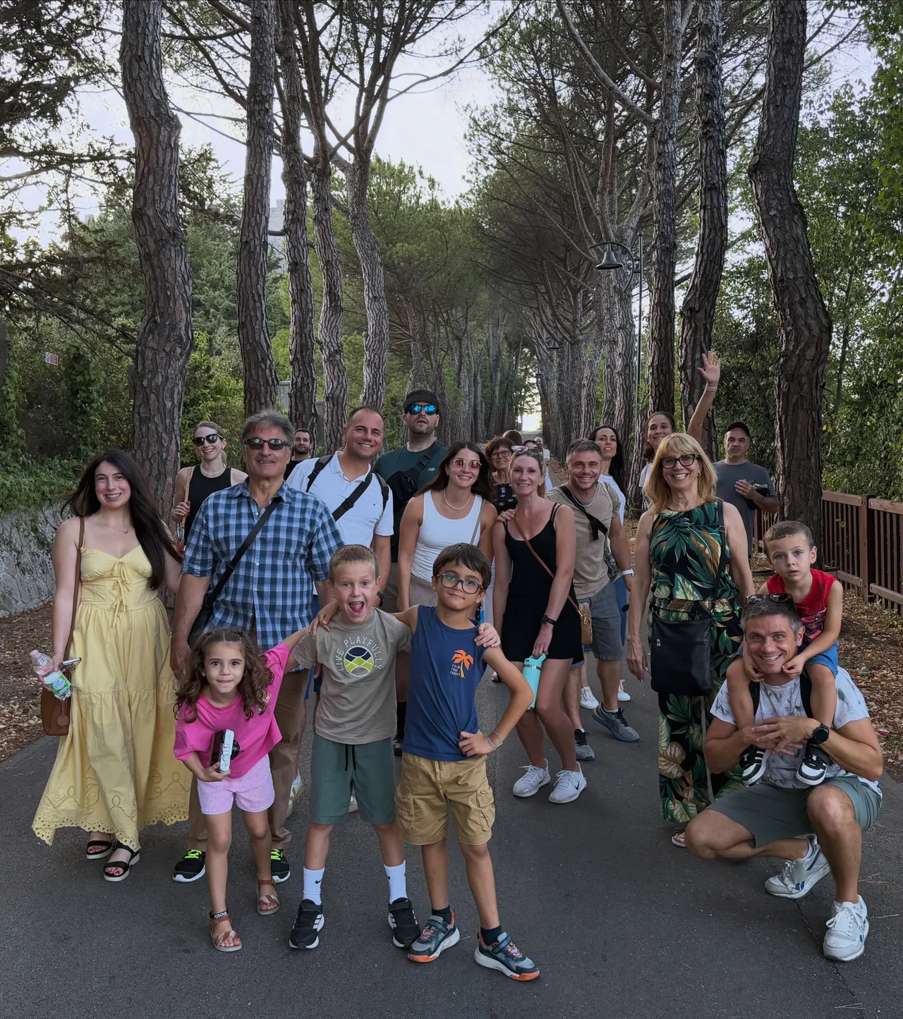 A large multigenerational family group on a pine-lined path