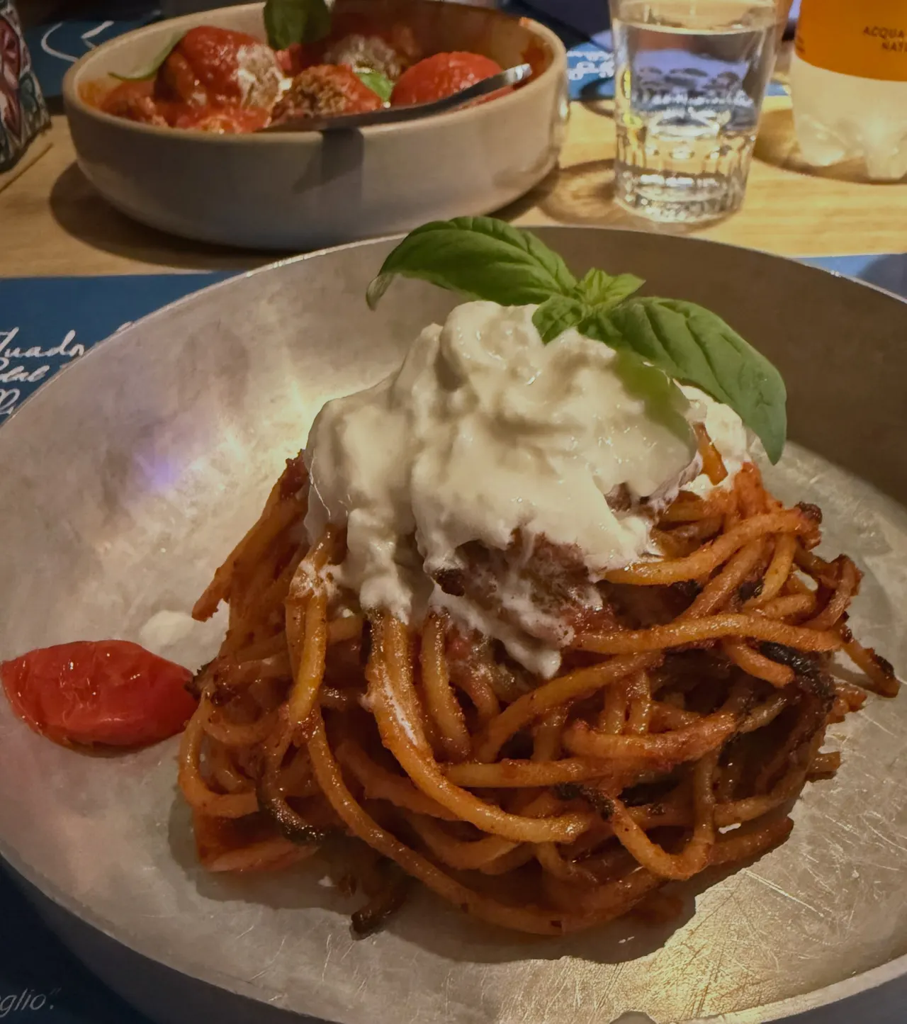 A plate of spaghetti topped with burrata