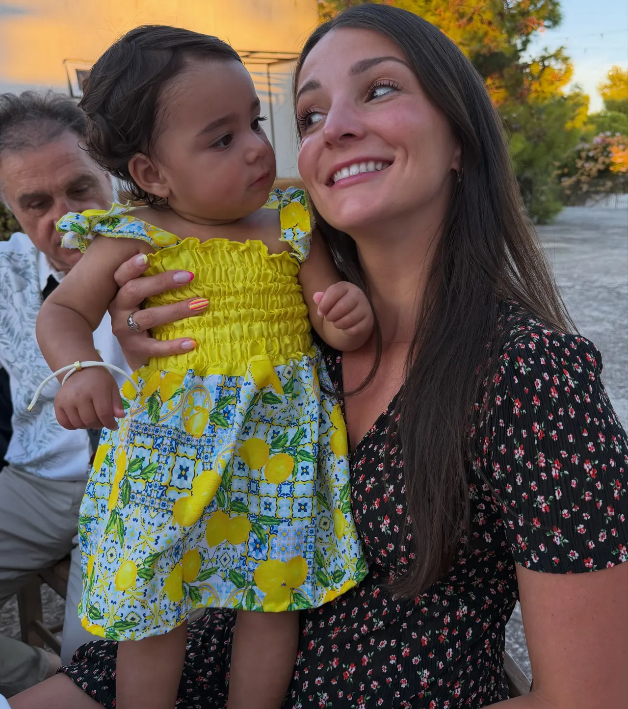 Valerie in a lemon-print dress holding a baby at sunset